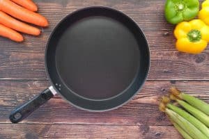 black frying pan with peppers carrots celery on wood