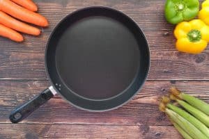 black frying pan with peppers carrots celery on wood