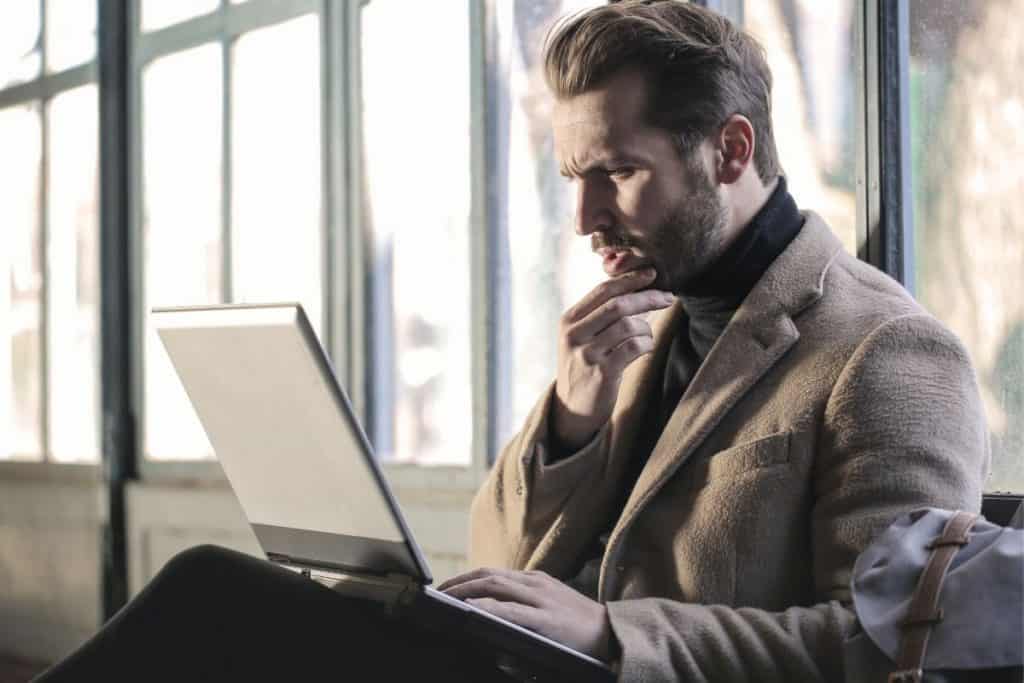 blonde man sitting down in front of a laptop