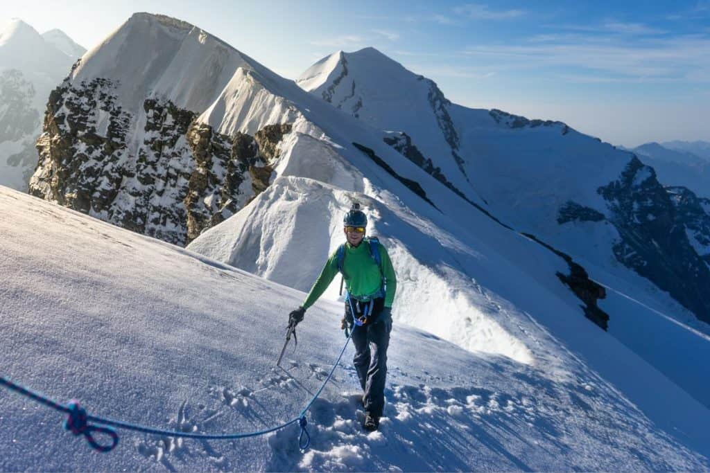 man in green shirt walking on snow on mountain
