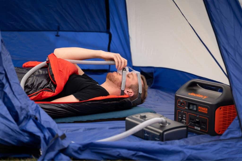 man lying down with cpap in blue tent