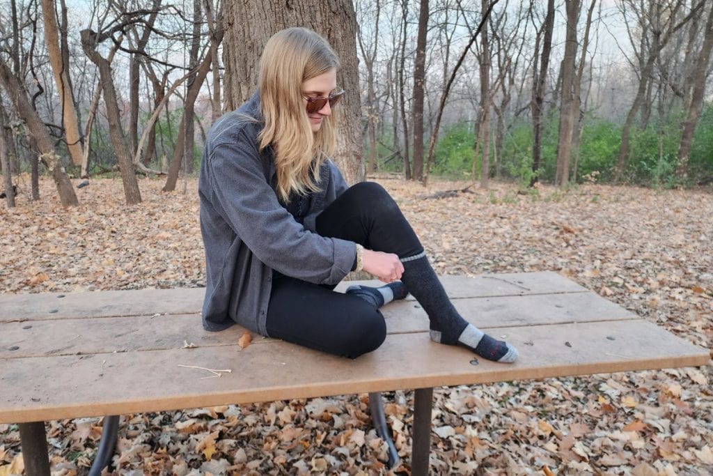 woman sitting on a picnic table pulling up socks