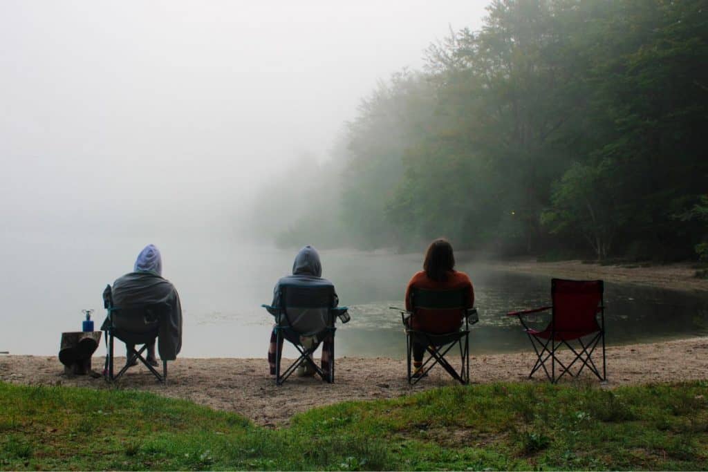 people sitting in chairs in front of a foggy lake