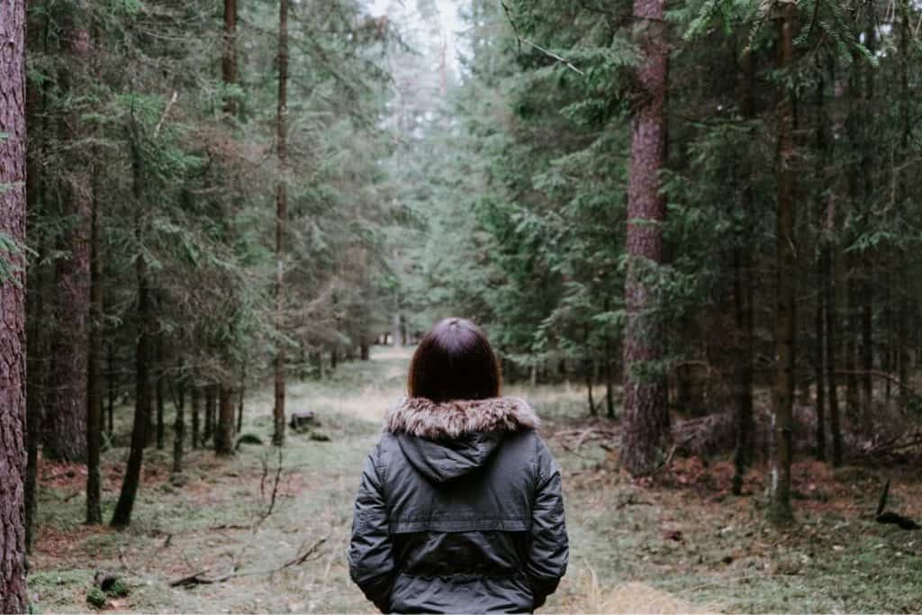 woman standing in the woods with a fluffy jacket