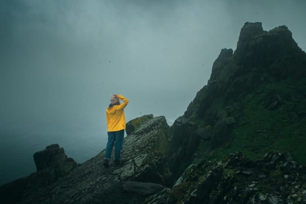 woman in yellow jacket standing on mountain in rain