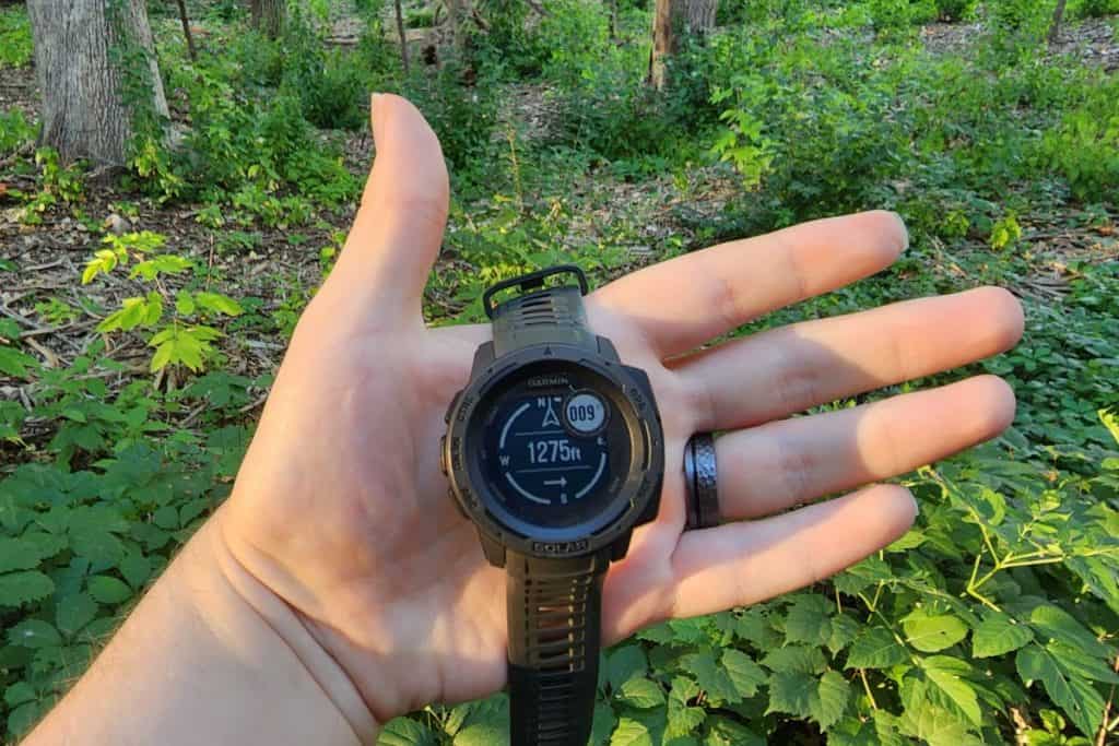 hand holding a watch in a forest