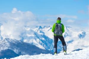 person in green coat standing on a snowy mountain