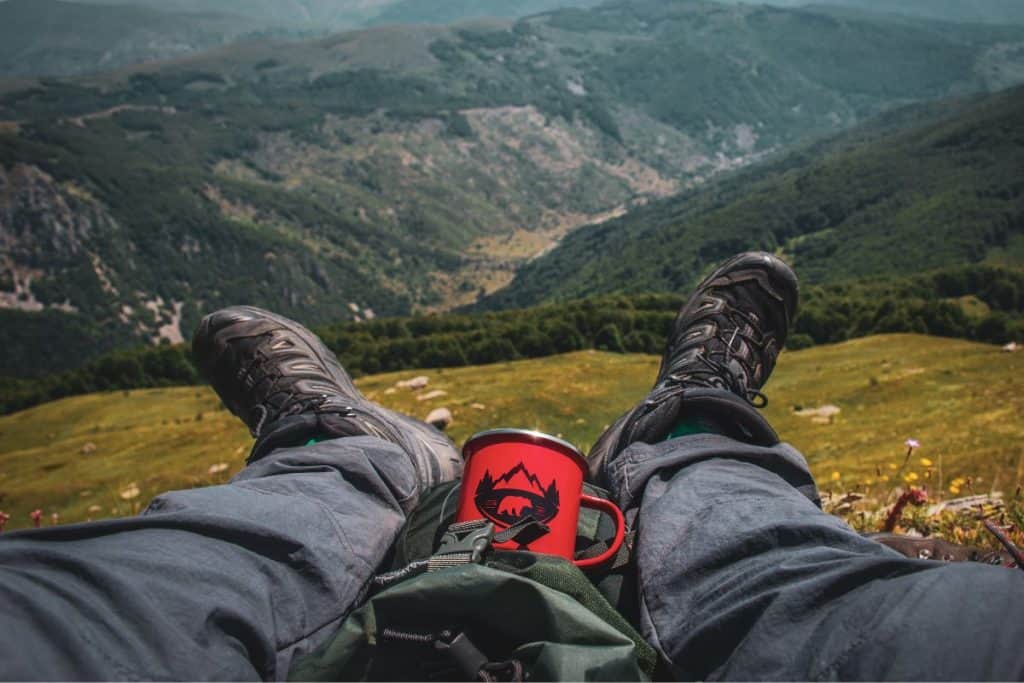 legs gray pants red cup hiking boots mountains