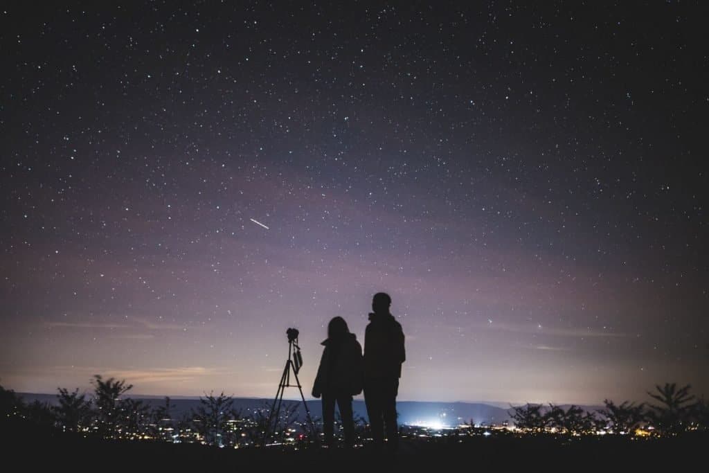 two people staring up at the stars in the night sky