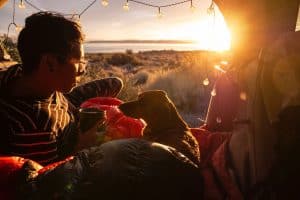 man sitting with dog in tent at sunset