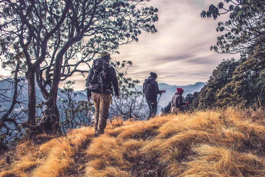 people walking down a trail with backpacks and trekking poles