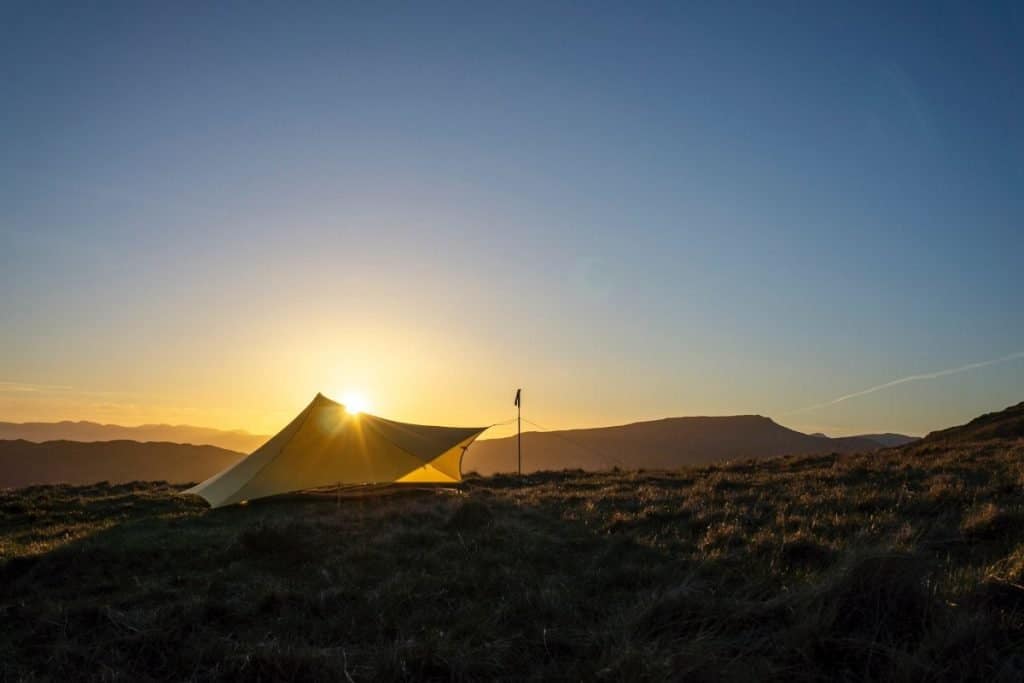 green tarp set up on a plane at sunrise