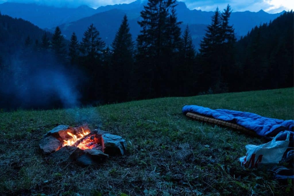 people sleeping outside next to a firepit