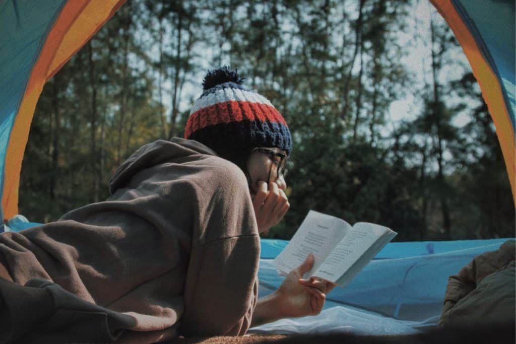 woman lying in a tent reading a book