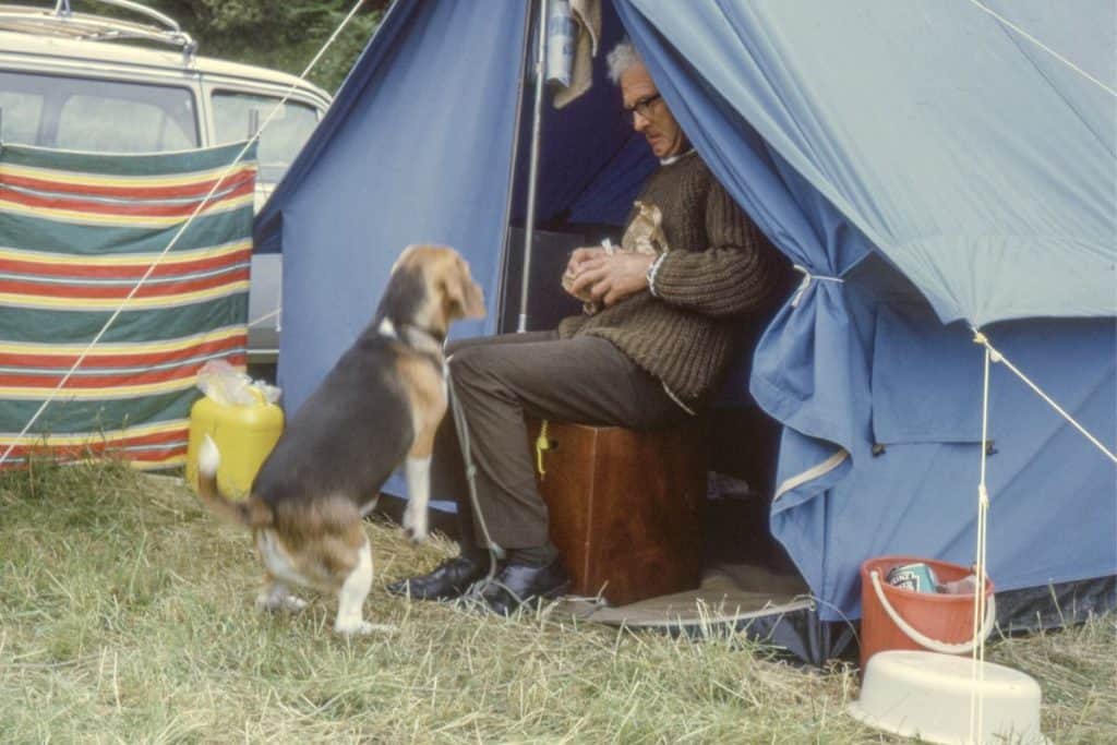 man sitting in a blue tent with a dog