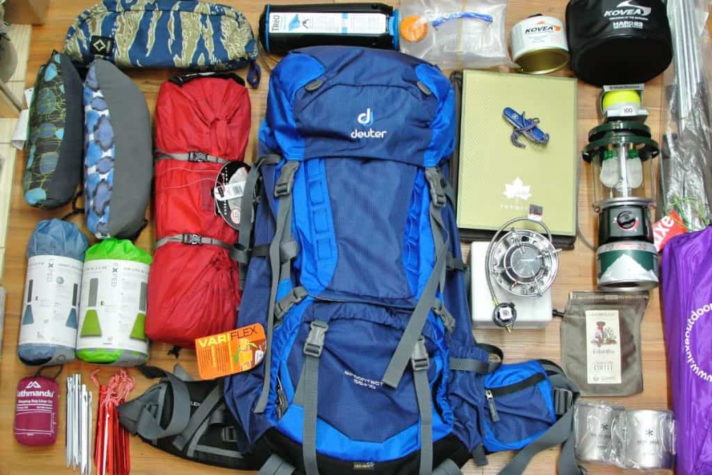 blue backpacking red sleeping bag camping gear on a wood surface