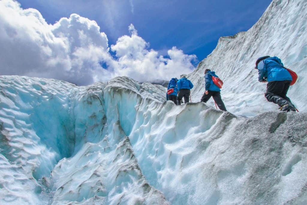 group of hikers climbing a snowy glacier