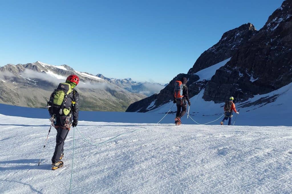 three people hiking through the snow in the mountains