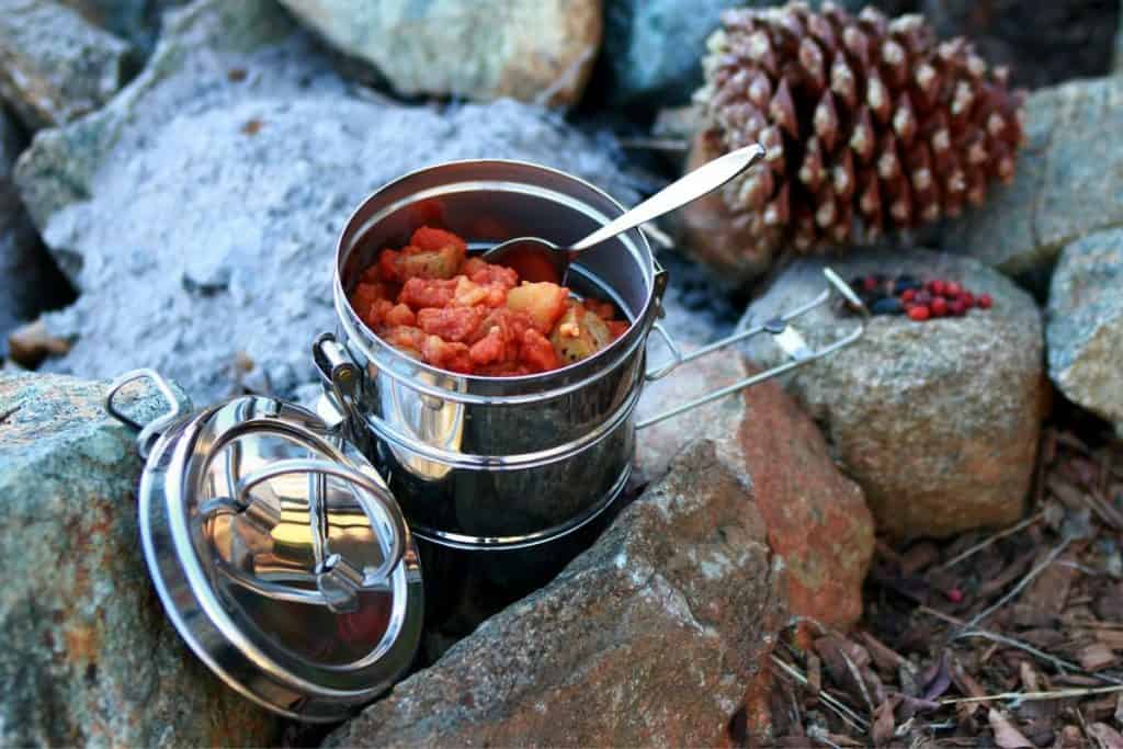 metal pot with red food on a rock