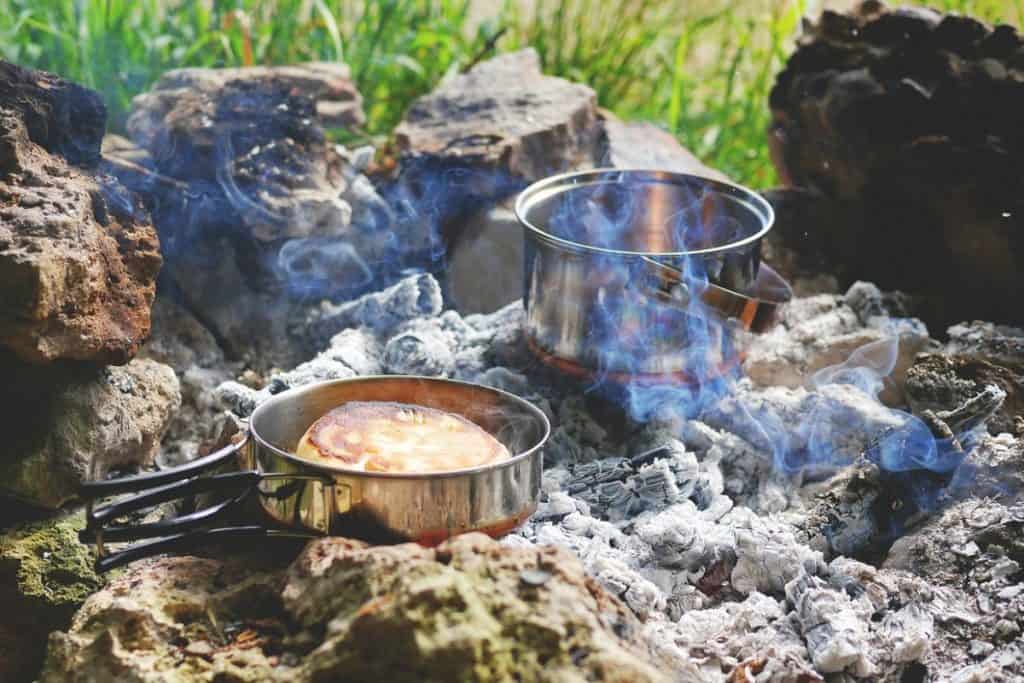 two metal pots with food over an open fire