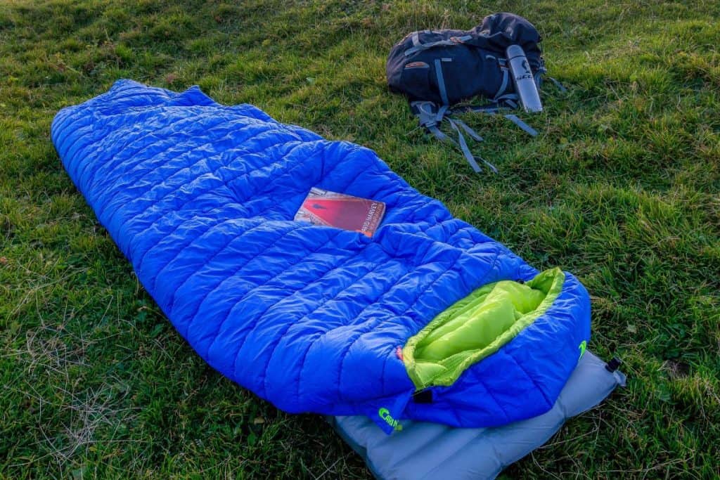 blue and green sleeping bag on the green grass