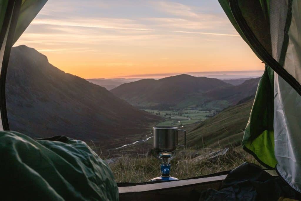 looking outside a tent at mountains and grass