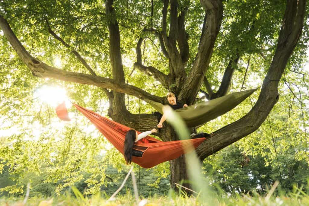 man and woman in hammocks touching each other