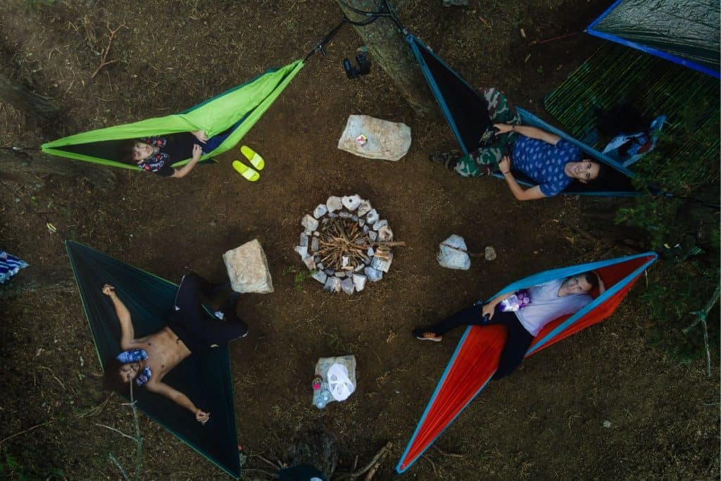 four people in a green, red, blue, and black hammock