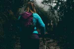 woman in blue coat and purple backpack hiking