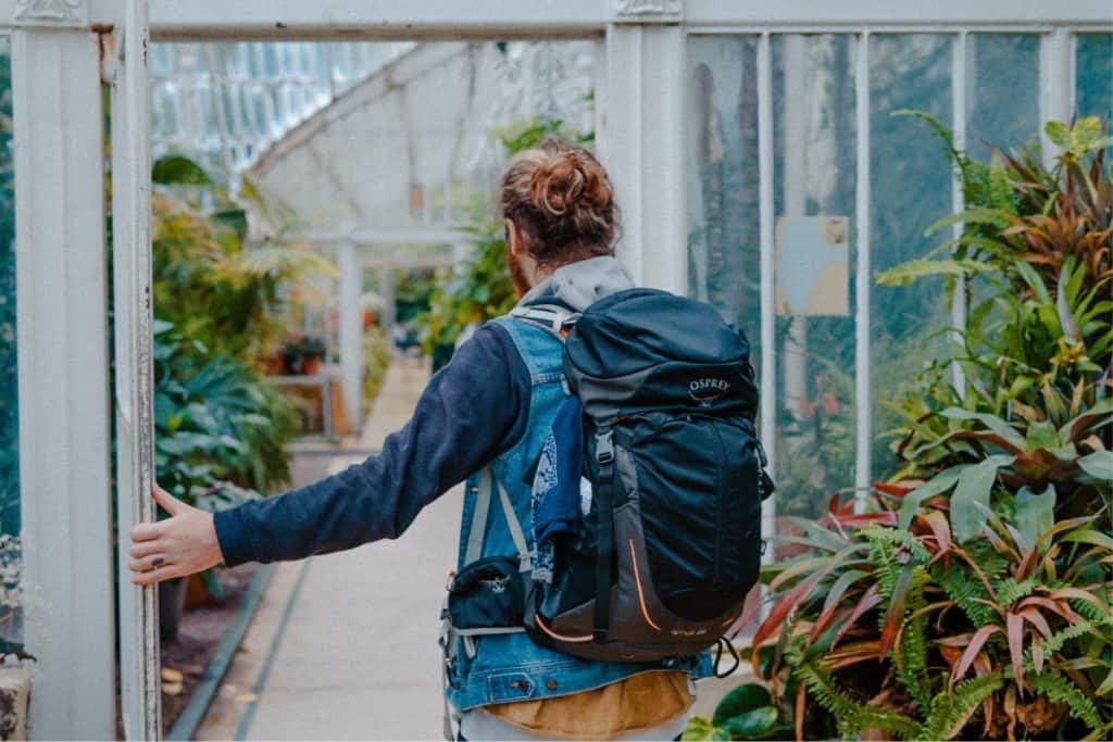 man with blue coat and blue backpack walking through a building