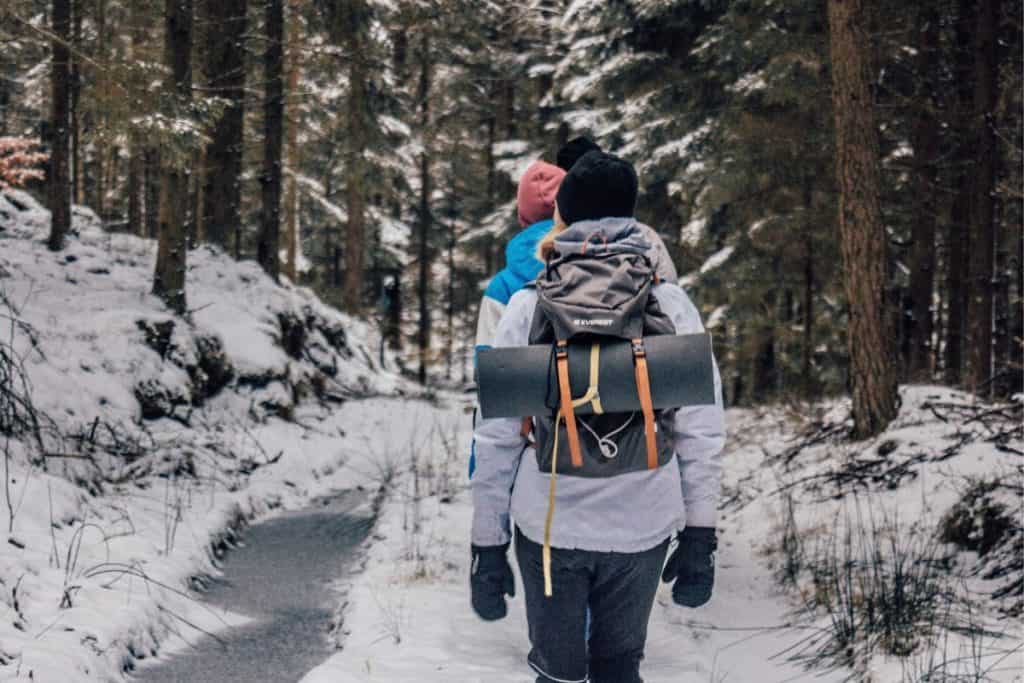 women hiking through a snowy trail with backpacks