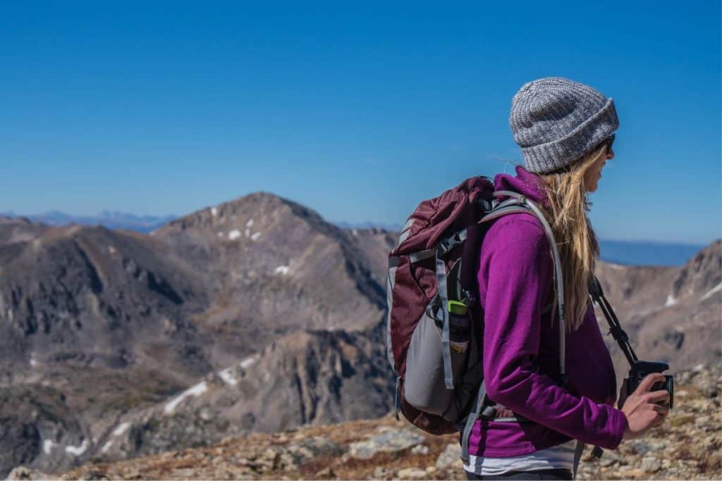 woman in purple jacket with backpack in the mountains