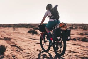 person riding a bike over red rock with a backpack and gear