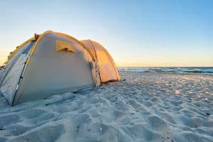 cream tent on sand at the beach by water