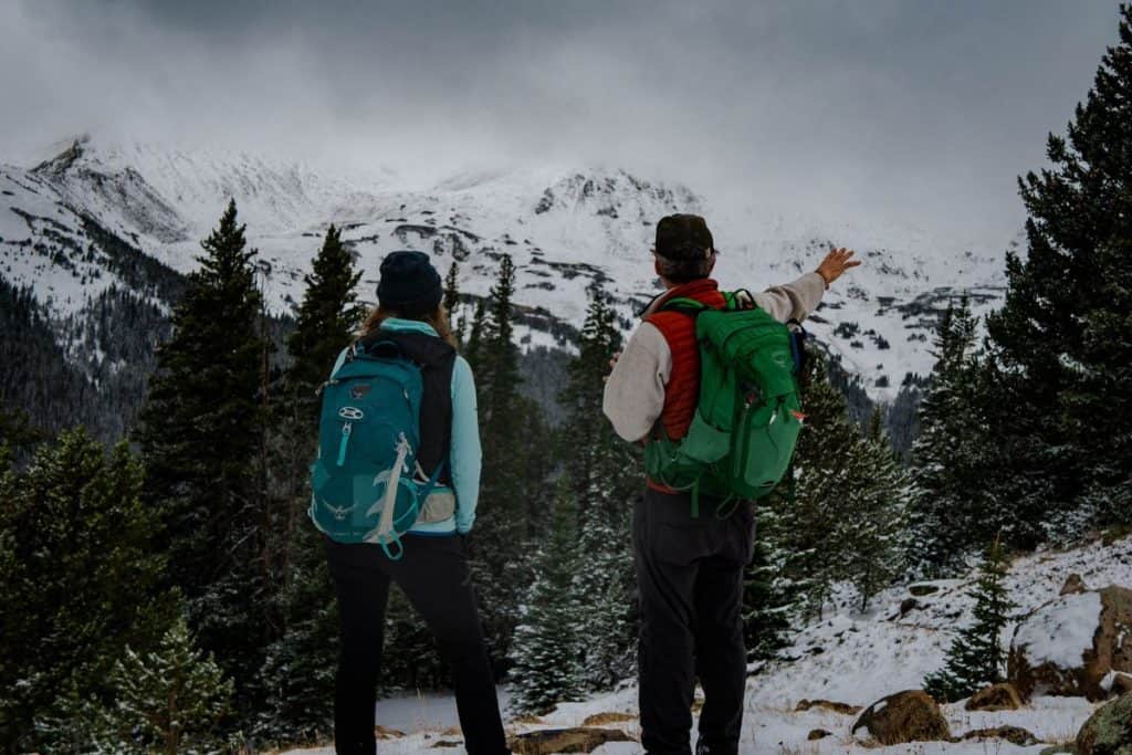 a man and woman with a green and blue backpack in the mountains