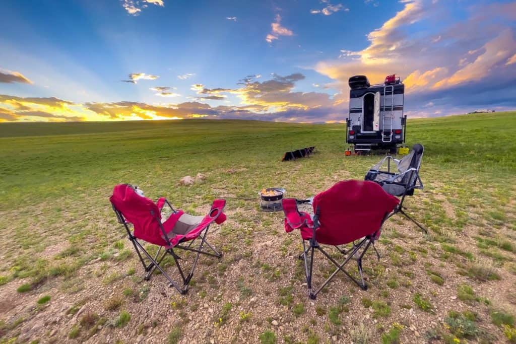 two red chairs on a grassy plain with an RV