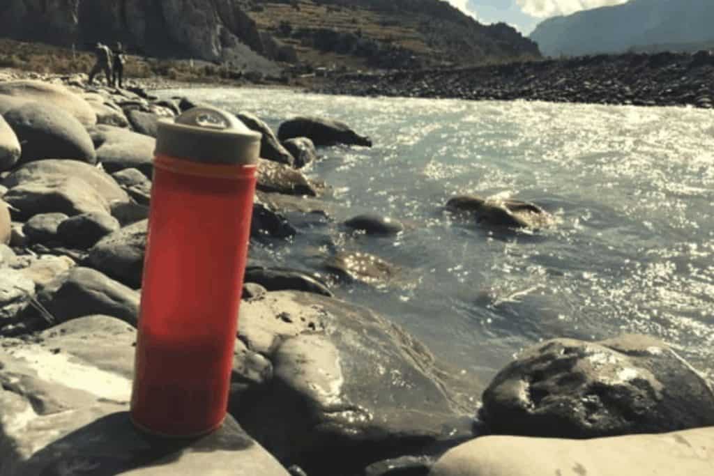 orange water bottle by river in nepal