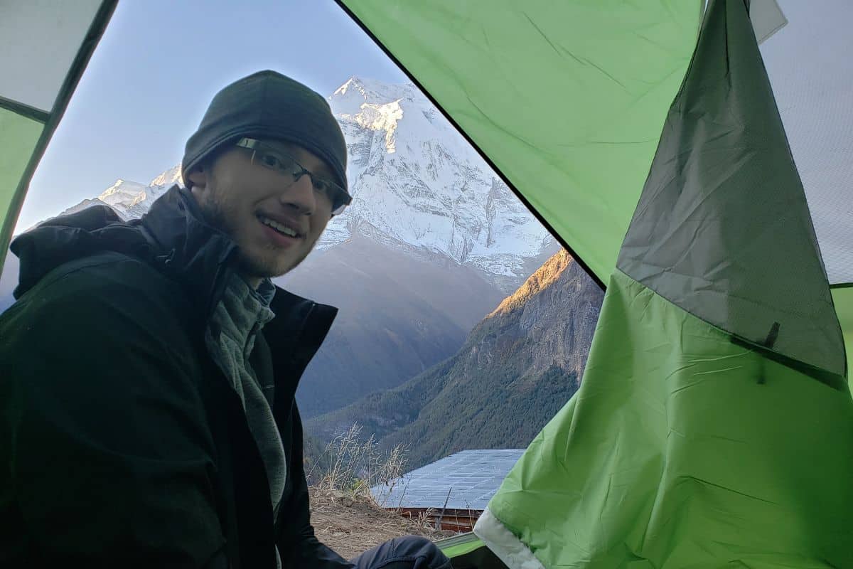 man sitting in a green tent in the himalayas