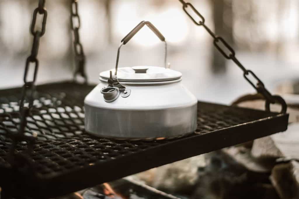 silver kettle on a platform above a fireplace