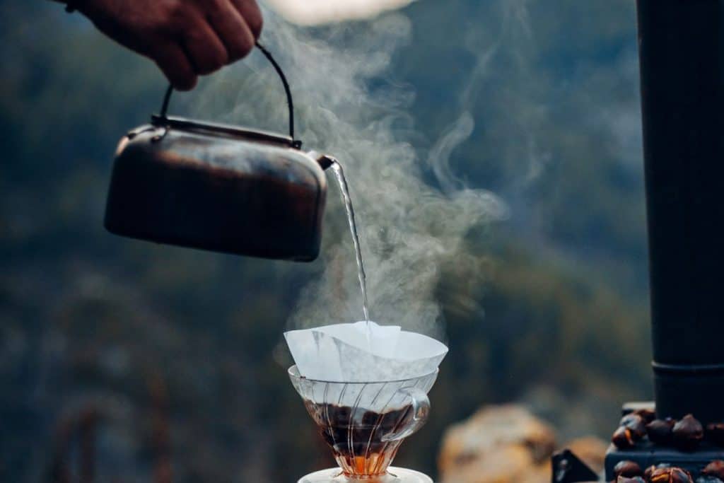 man holding kettle pouring water into a filter