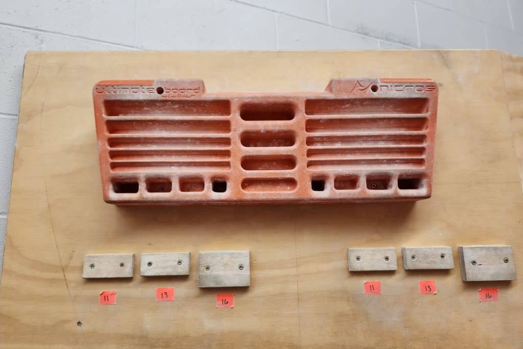 orange hangboard mounted on a wall