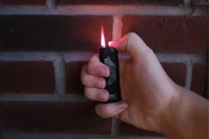 man holding a lighter against a brick wall
