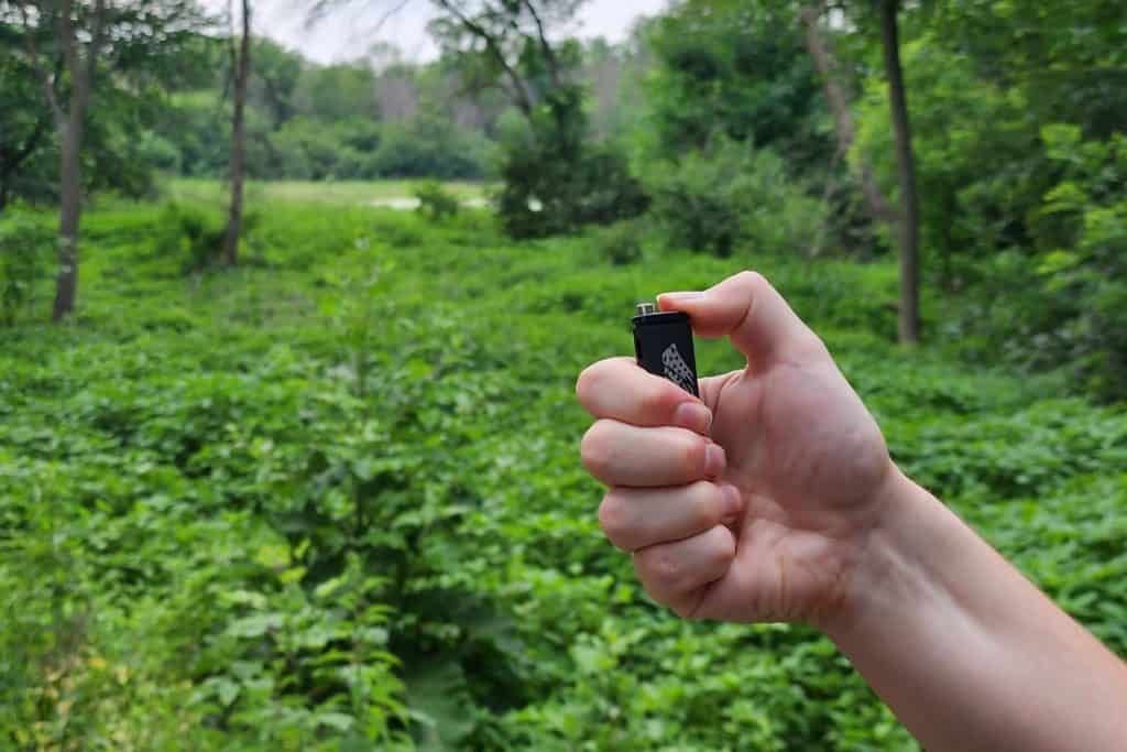 The Best Camping Lighter in 2023 3 man holding a lighter in a green forest