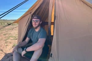 man in blue shirt sitting in a canvas tent in the desert