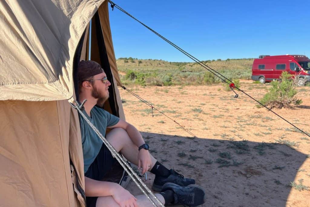 man sitting in a canvas tent in the desert
