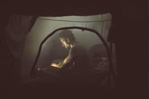 man sitting in a tent at night