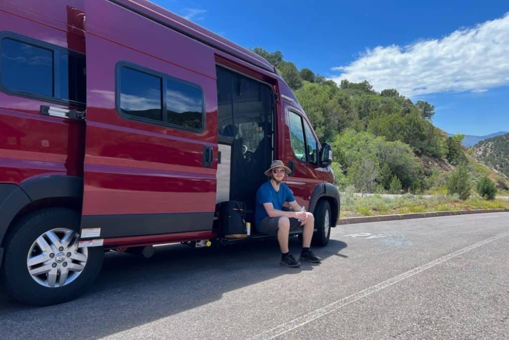 man in blue shirt sitting in a red van zion national park