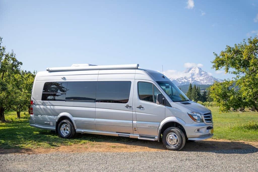 silver sprinter van parked on gravel in front of a mountain