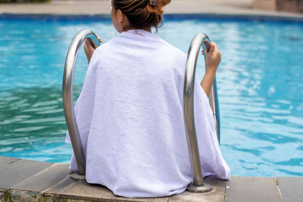 girl sitting at a pool with a towel around her shoulders