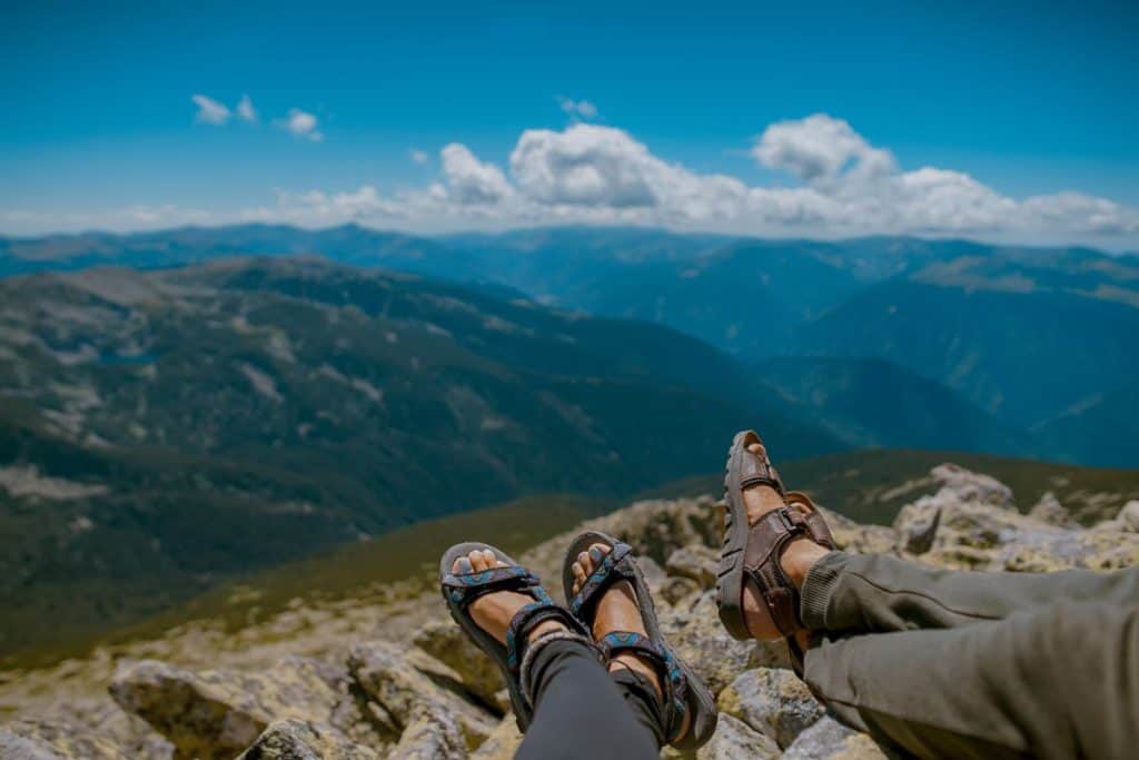 two people's feet with hiking sandals in the mountains